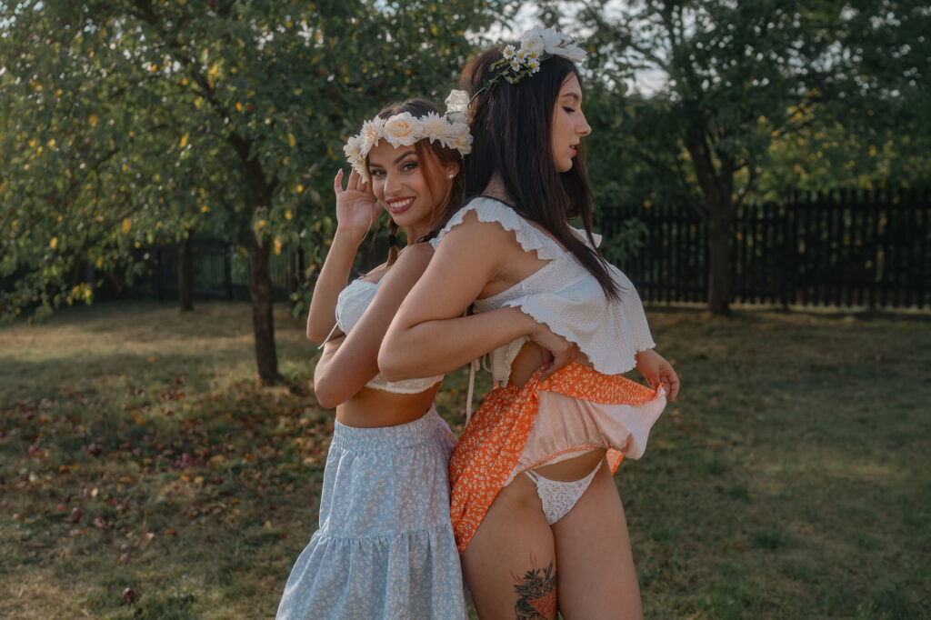 Two models with flower crowns lifting a folk skirt in a garden, HotFolk 2024 calendar