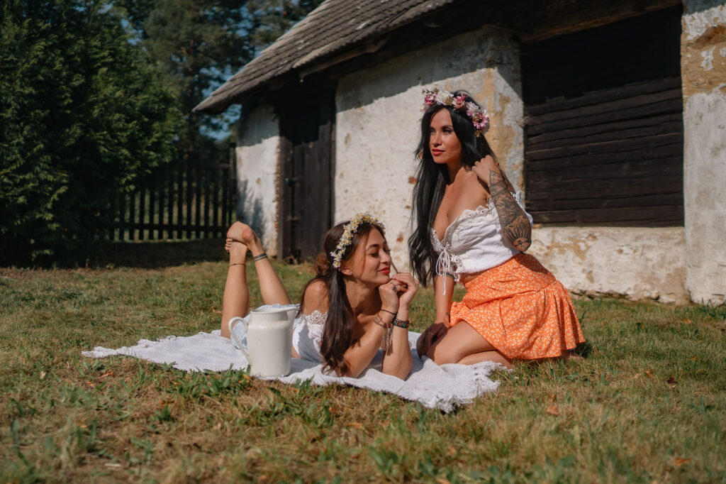 Two models on a white blanket in front of an old cottage, HotFolk 2024 calendar
