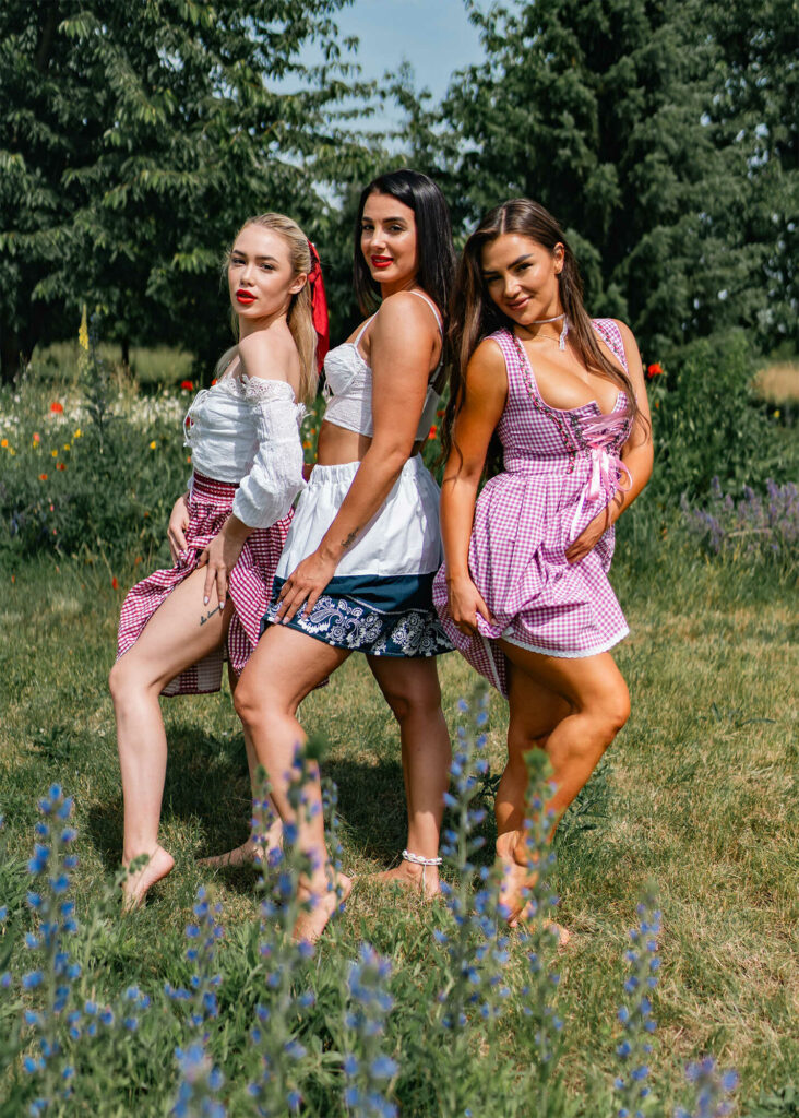 Three models in traditional Czech folk dress standing together in a summer garden, HotFolk calendar photoshoot