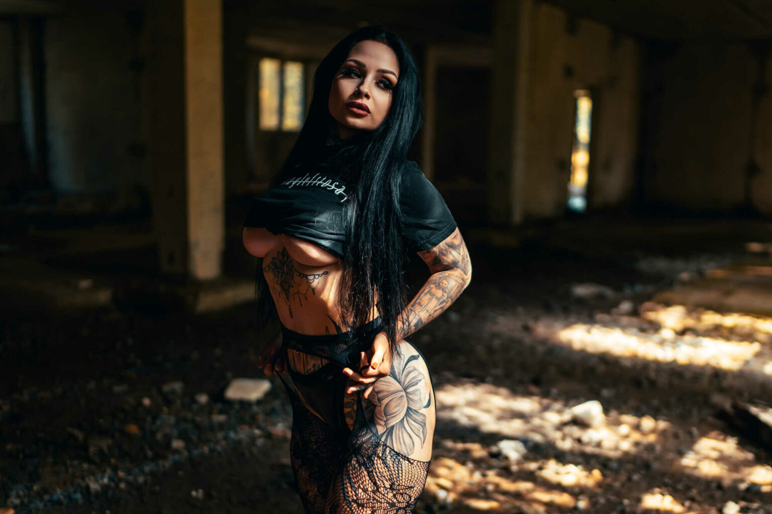 Tereza in fishnets standing in golden light inside an abandoned building