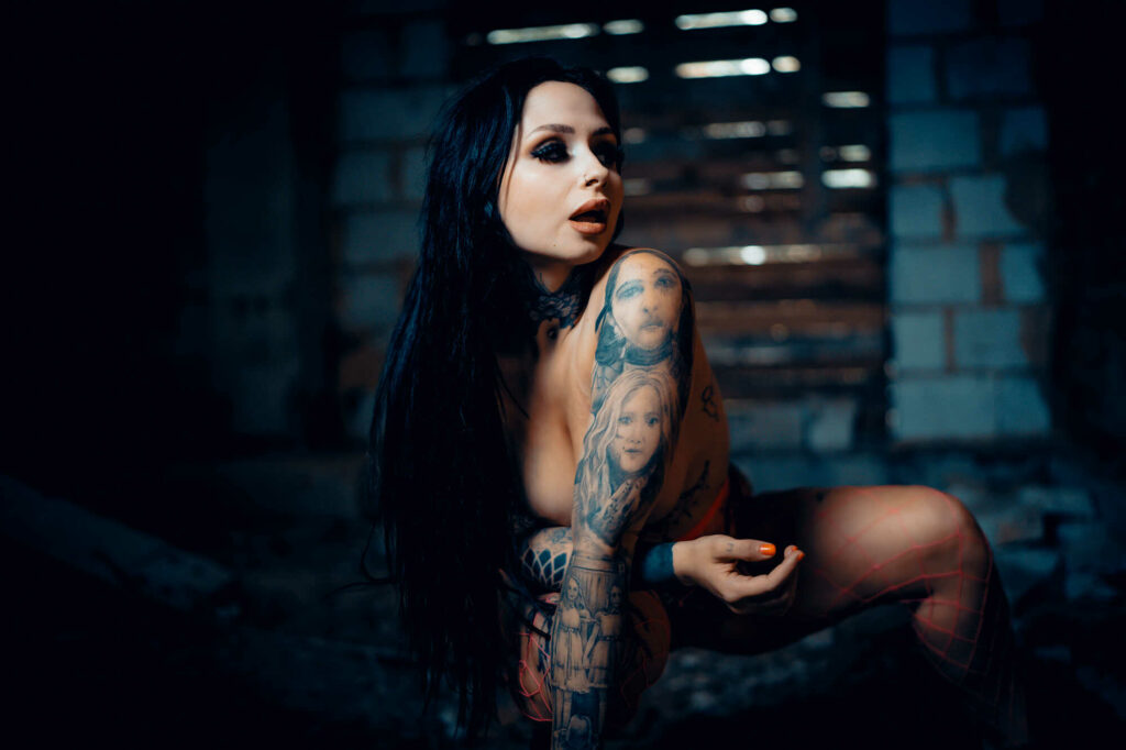Tereza sitting in a dark room, tattoos lit by a window