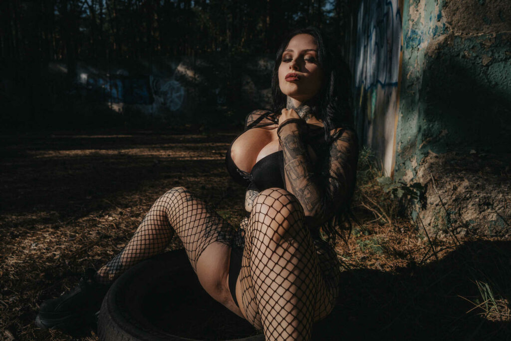 Tereza in fishnet stockings sitting in a dark forest