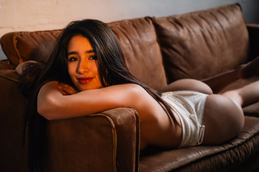 Mexican model Sofia posing in a white bodysuit on a leather couch