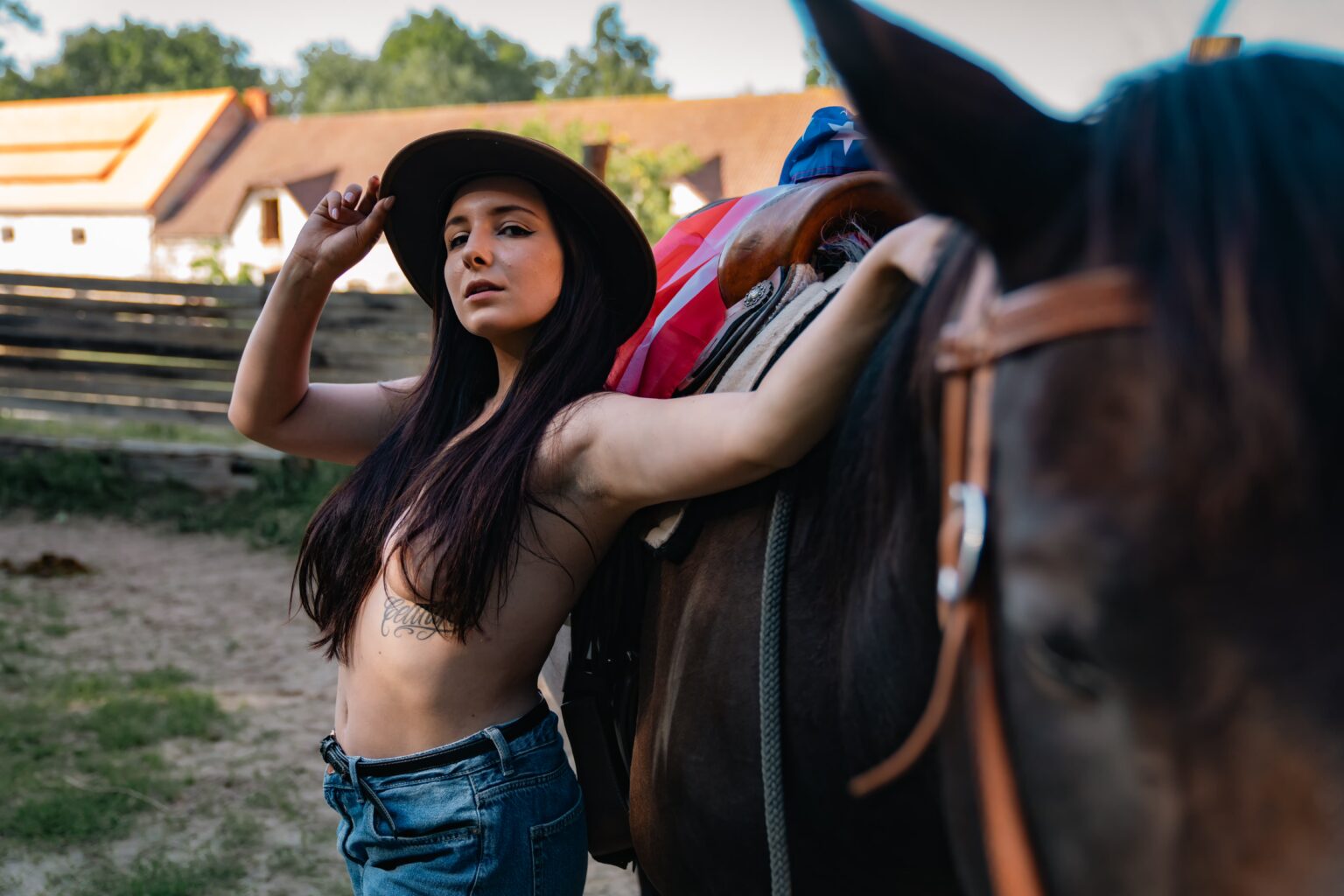 Nikol posing with a brown horse and cowboy hat during an outdoor countryside photography session.