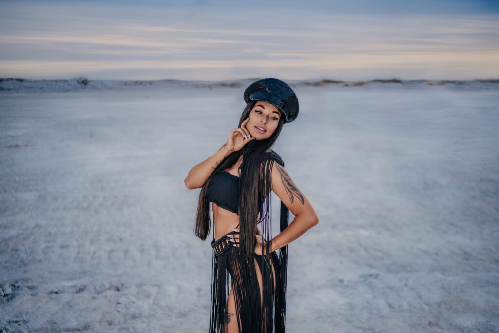 Jana walking across desert dunes, Gurning Man-inspired costume flowing, warm light
