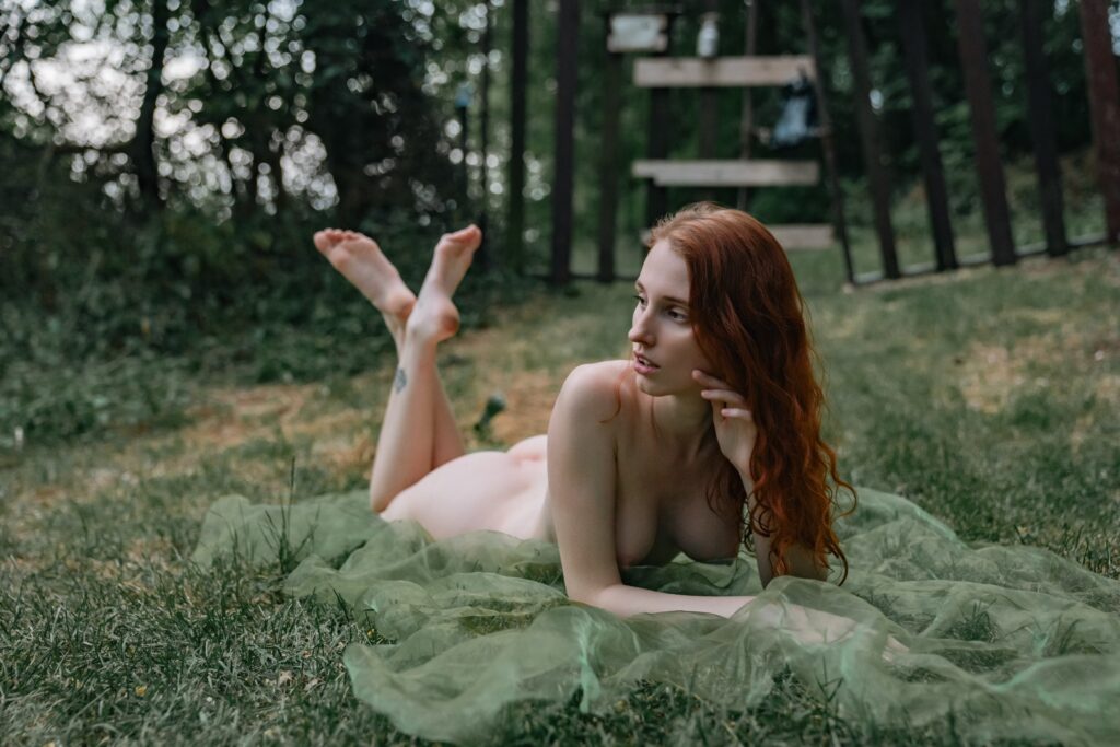 Kuro Rain lying nude in the grass with green fabric, legs raised