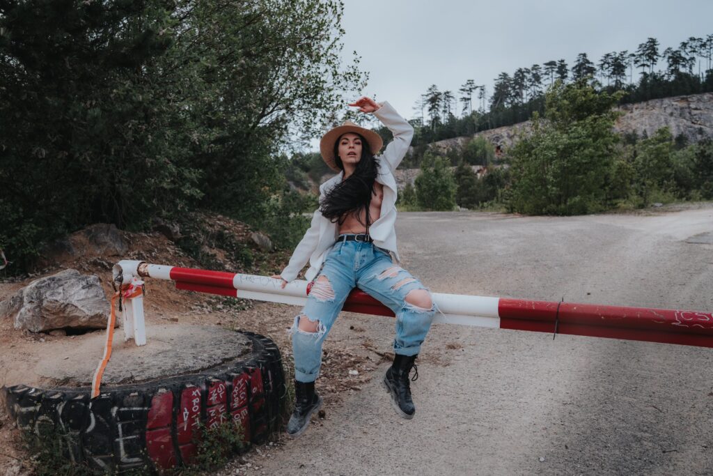 MovenModel posing on a barrier in a loose blouse and hat