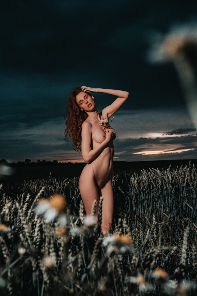 Kuro Rain standing nude in a meadow under a dark storm sky