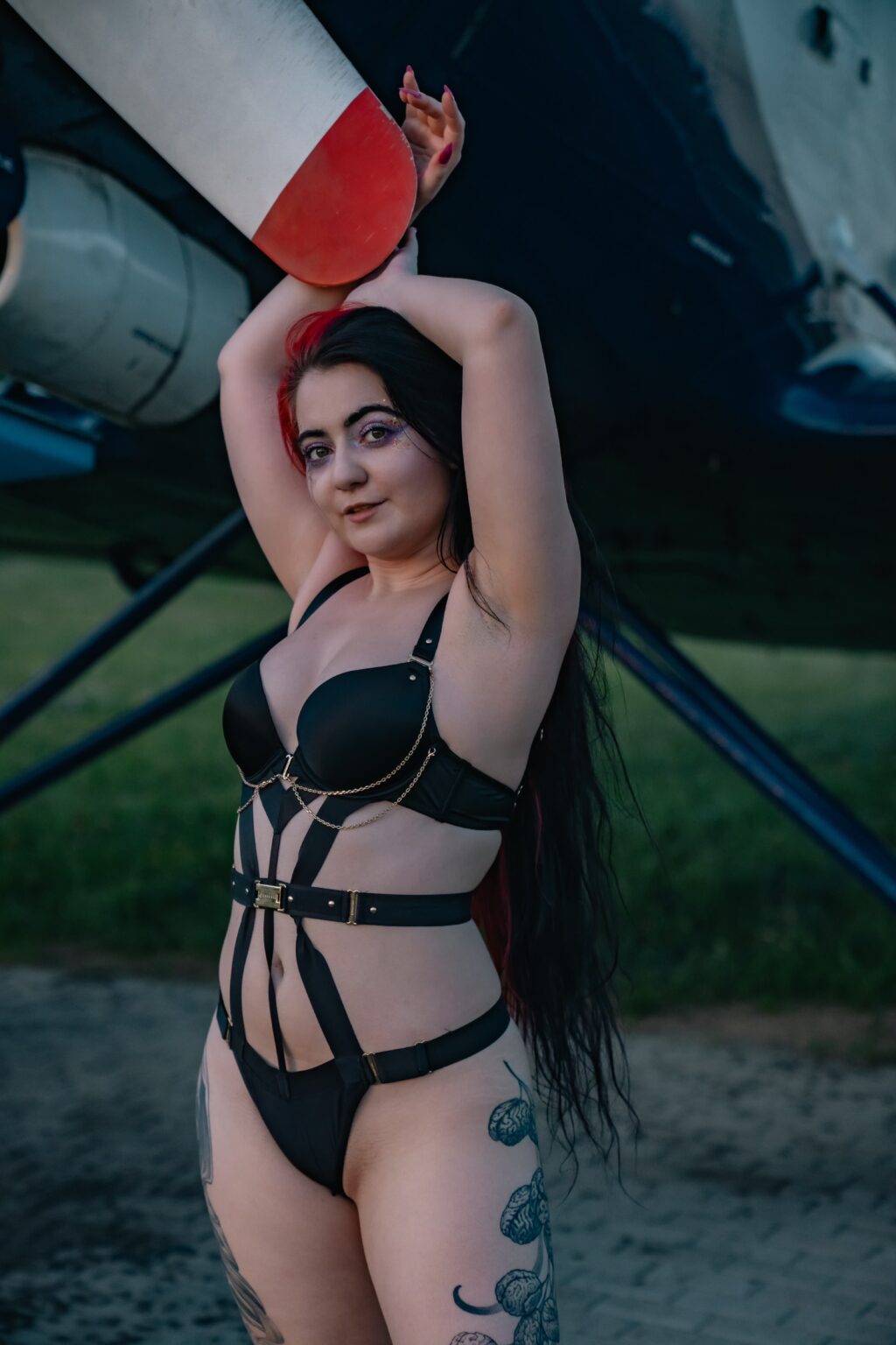 Natali in black strappy lingerie by an old aircraft