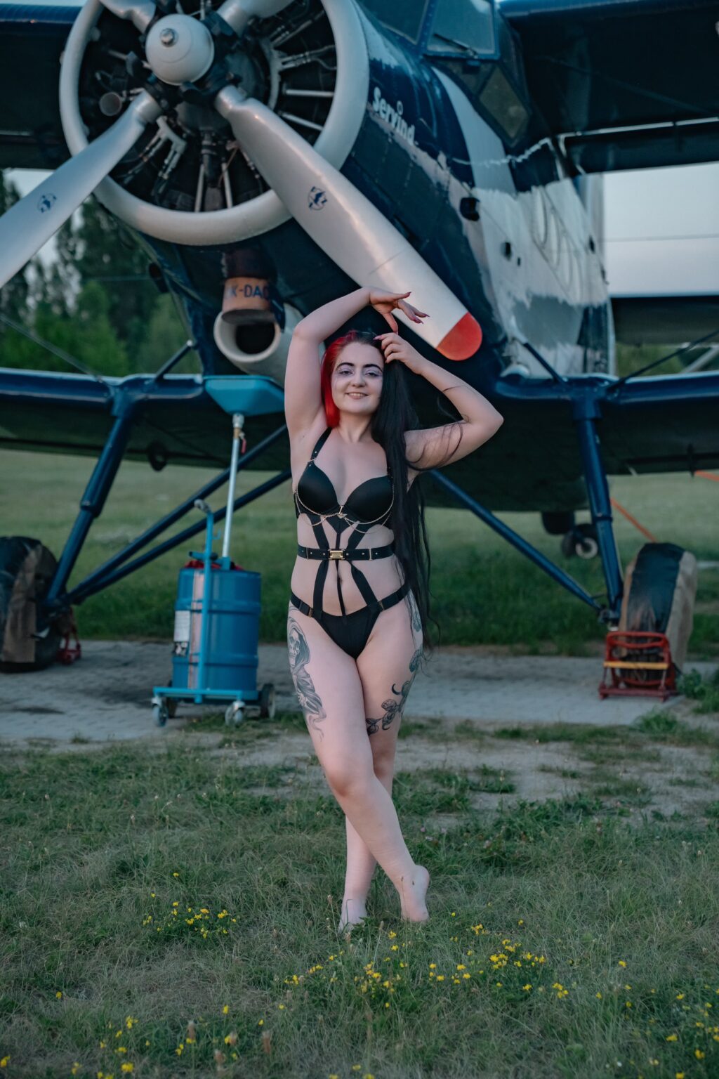 Natali posing in front of an airplane parked outside an old hangar