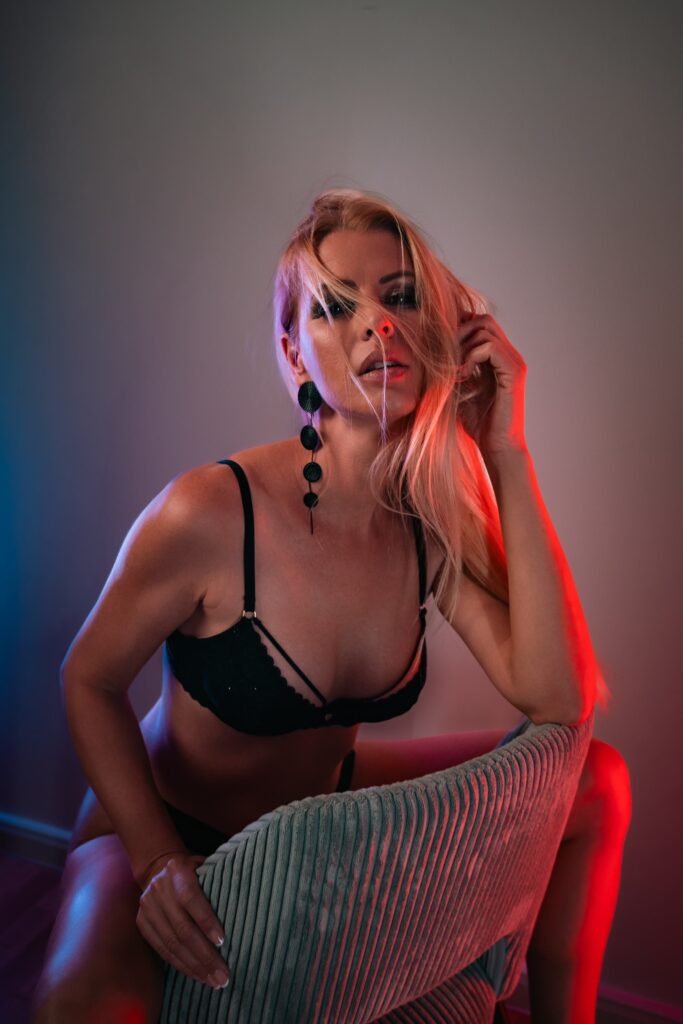 Lynna Nilsson posing on a chair and removing her lingerie