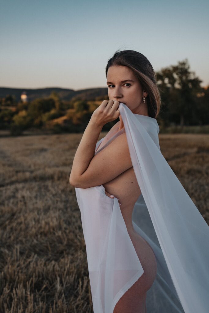 Won't Tell You draped in sheer white fabric in a field at sunset