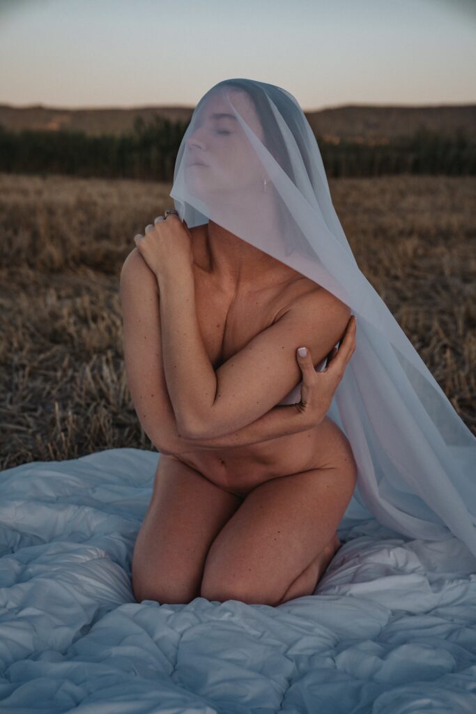 Won't Tell You kneeling nude under a white veil in a field