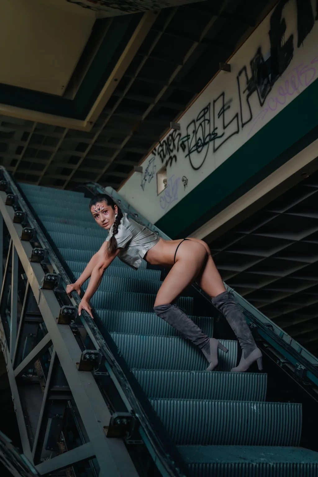 Jitka reclining in grey on the steps of an abandoned escalator