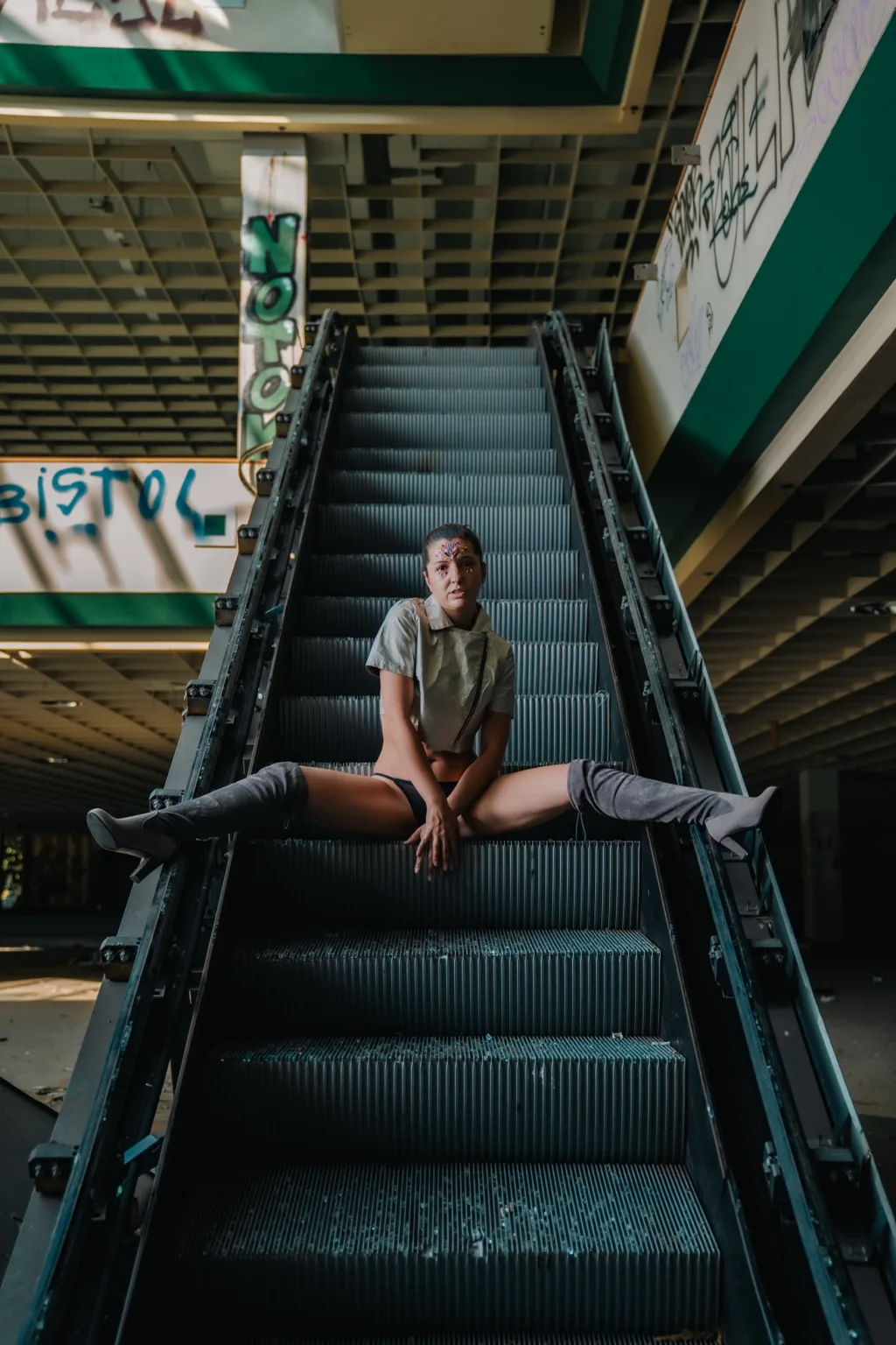 Jitka sitting on an abandoned escalator viewed from below