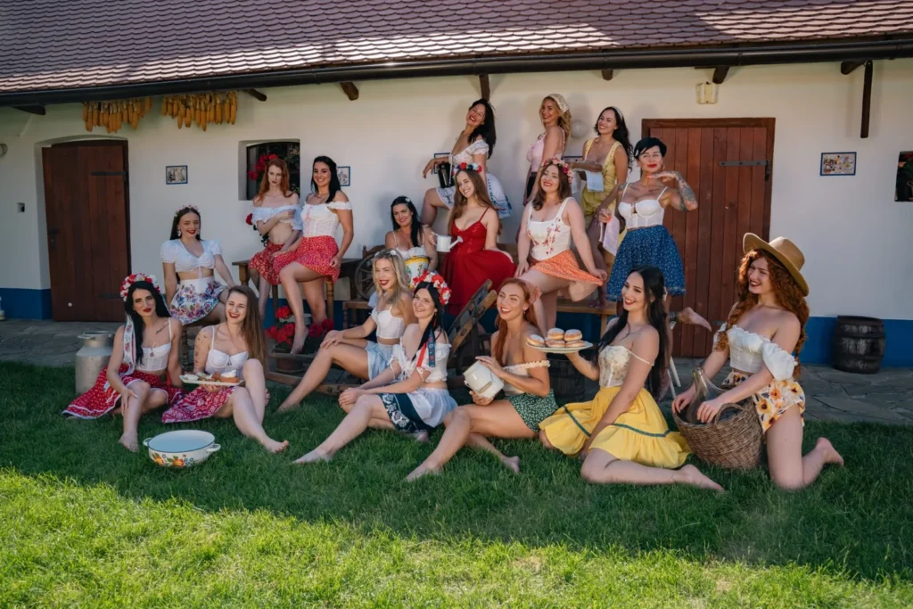 The whole HotFolk 2027 cast in folk outfits in front of a Moravian farmstead