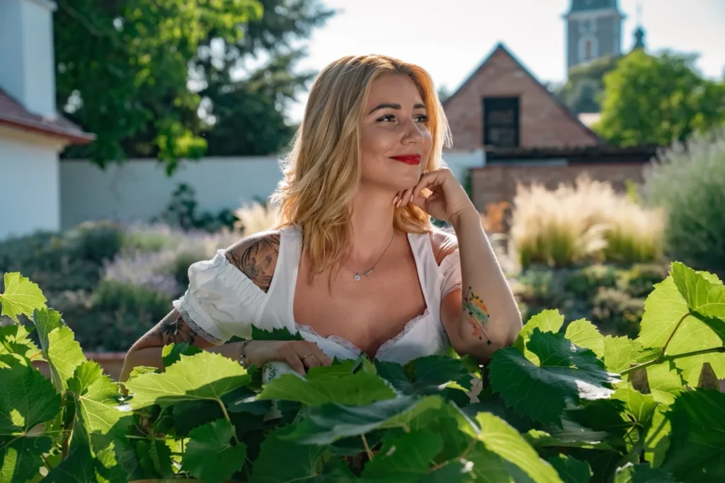 Blonde model in a white folk blouse among vine leaves at a Moravian farmstead, HotFolk 2027 calendar